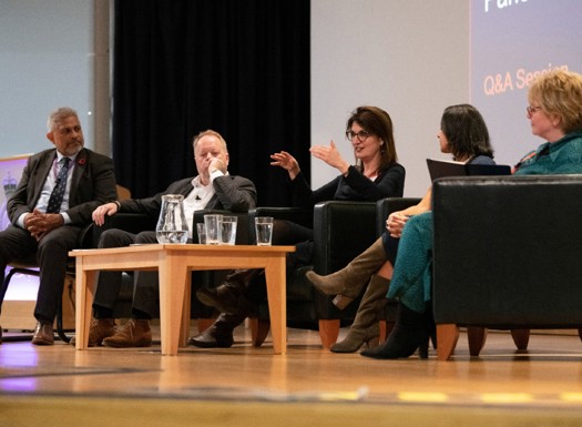 A group of individuals seated on chairs on stage for a Q&A session.