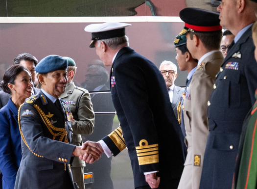 A senior British Navy officer greeting the Sultan of Brunei as he disembarked a coach.
