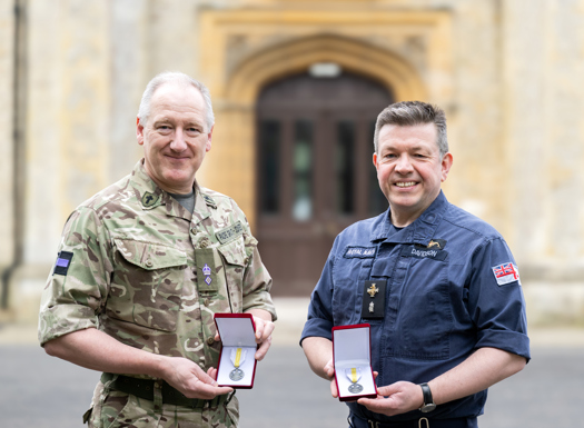 An Army and Navy padre holding their Ukrainian medals in their presentation boxes.
