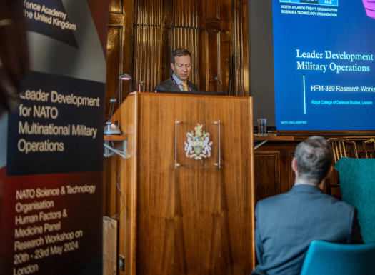 A man presenting behind a lectern at a NATO workshop