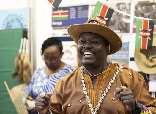 A black man wearing national dress while smiling. 