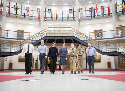 Tri-service personnel walking through the Forum with international flags hanging above them.