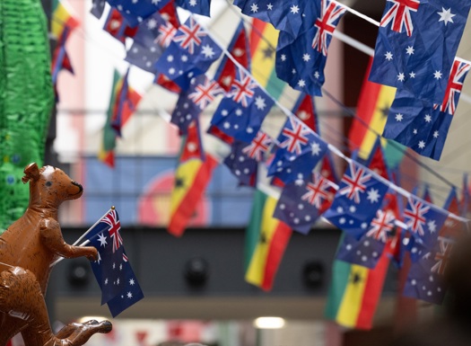 Rows of Australian flags hanging above a street with a inflatable kangaroo holding a small Australian flag in the foreground.