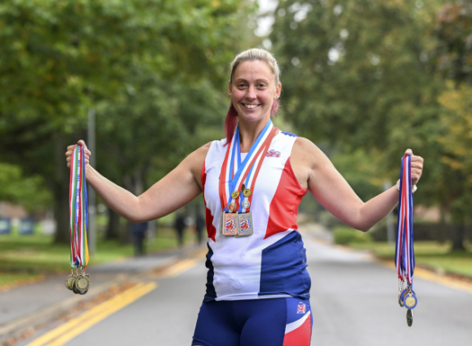 A women stood outside holding up her European Athletics medals.