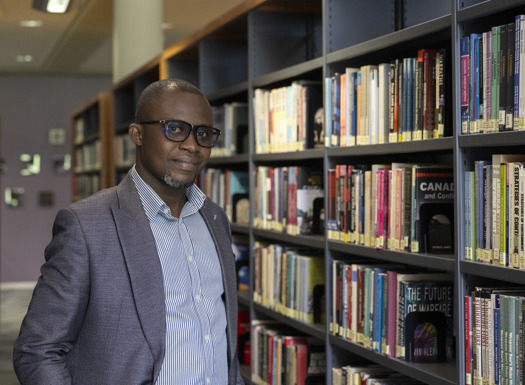 A person led against a large bookcase inside a library. 