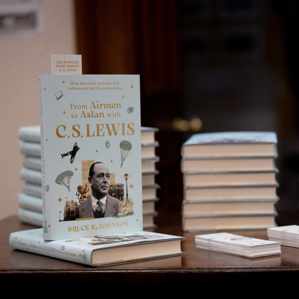 Stacks of the book 'From Airmen to Asian with C.S. Lewis' by Bruce Robinson displayed on a table, with one copy standing upright showing the cover.