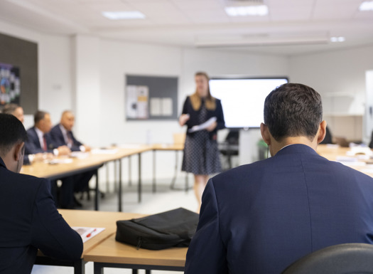 Students in a classroom being spoken to by instructor. 
